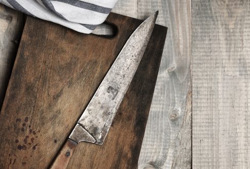 rostiges Messer auf einem dunkeln Holzbrett